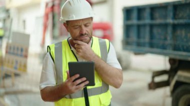 Middle age man architect using touchpad at street
