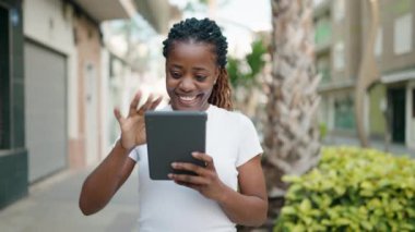 African american woman smiling confident using touchpad at street