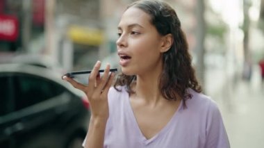 Genç Afrikalı Amerikalı kadın gülümsüyor. Kendine güveni tam. Sokakta akıllı telefondan konuşuyor.