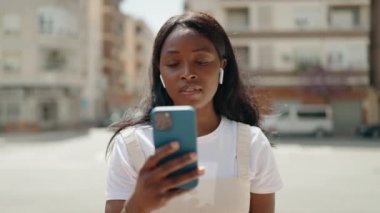 Young african american woman listening to music at street