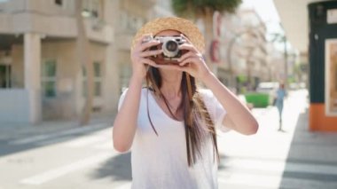 Young hispanic woman tourist smiling confident using camera at street