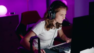 Young beautiful hispanic woman streamer playing video game using computer at gaming room