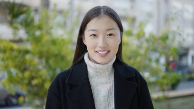 Parkta kendinden emin gülümseyen genç Çinli kadın.