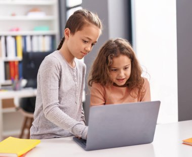 Two kids students using computer studying at classroom