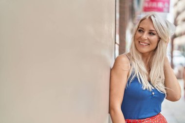 Young blonde woman smiling confident looking to the side at street