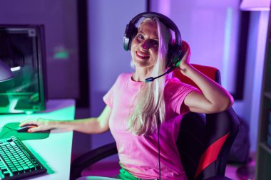 Young blonde woman streamer smiling confident using computer at gaming room