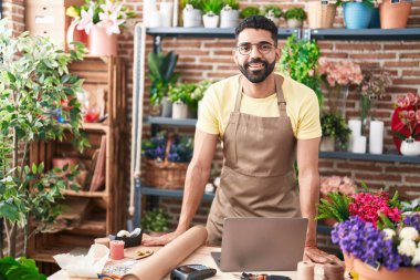 Young arab man florist smiling confident standing at florist