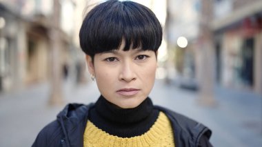 Young chinese woman standing with serious expression at street