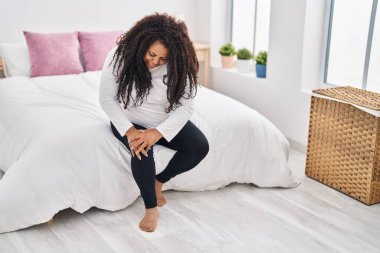 Afrika kökenli Amerikalı bir kadın dizinden sakatlandı. Yatak odasında oturuyor.