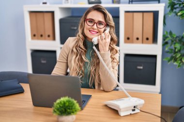 Young woman business worker talking on telephone at office