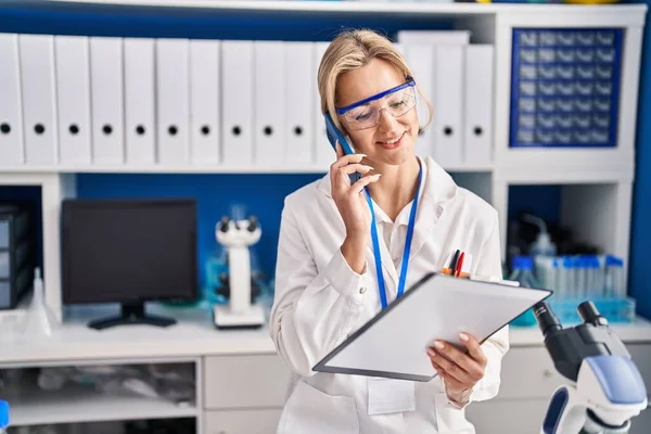 Young Blonde Woman Scientist Talking Smartphone Laboratory — Stockfoto