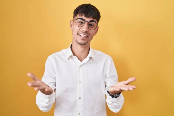 Nuori Latino Mies Seisoo Keltainen Tausta Hymyilevä Iloinen Tarjoaa Kädet — kuvapankkivalokuva