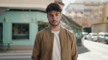 Genç İspanyol adam gülümsüyor. Kendine güveni tam. Sokakta çapraz hareketlerle duruyor.