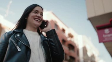 Genç İspanyol kadın gülümsüyor. Kendine güveniyor. Akıllı telefondan konuşuyor.