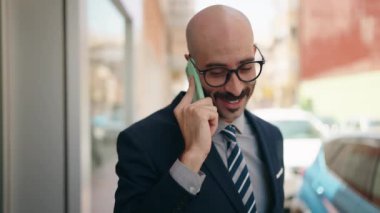 Young hispanic man executive smiling confident talking on smartphone at street