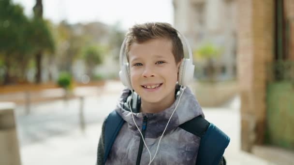 Sarışın Çocuk Kendinden Emin Bir Şekilde Gülümsüyor Sokakta Müzik Dinliyor — Stok video