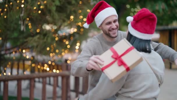 Junges Paar Mit Weihnachtsmütze Überrascht Mit Geschenk Park — Stockvideo