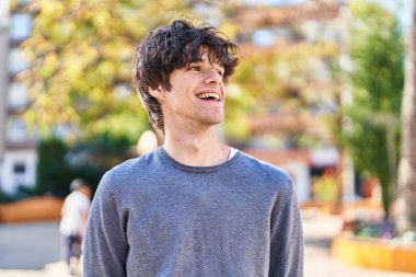 Parkta kendinden emin gülümseyen İspanyol genç adam.