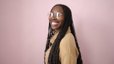 African woman smiling confident over isolated pink background