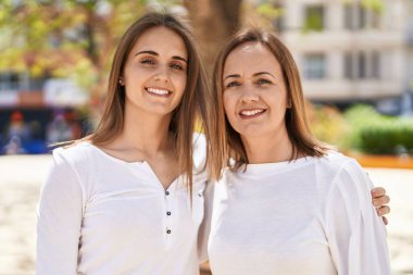 Two women mother and daughter hugging each other at park