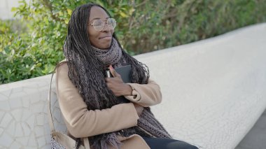 African woman hugging a book at park