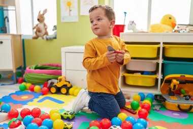 Sevimli beyaz çocuk, gülümsüyor. Anaokulunda oyuncakla oynuyor.