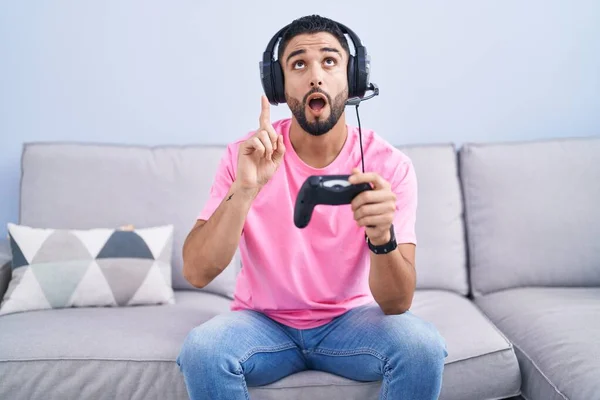 Hispanic Ung Man Spelar Spel Innehav Controller Sitter Soffan Förvånad — Stockfoto