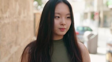 Young chinese woman smiling confident standing at street