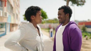 African american man and woman couple speaking together and kissing at street