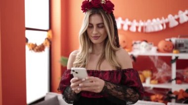 Young blonde woman using smartphone having halloween party at home