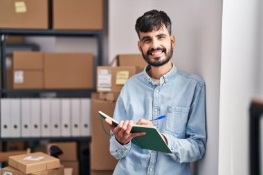 Young hispanic man ecommerce business worker writing on notebook at office