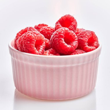  İzole edilmiş beyaz arka planda seramik kasede nefis ahududu grubu.