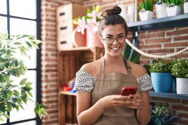 Çiçekçiye akıllı telefon kullanarak gülümseyen güzel İspanyol kadın.