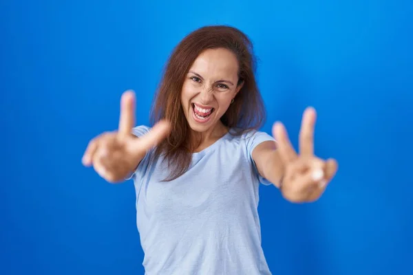 Brunette Woman Standing Blue Background Smiling Tongue Out Showing Fingers — Foto Stock