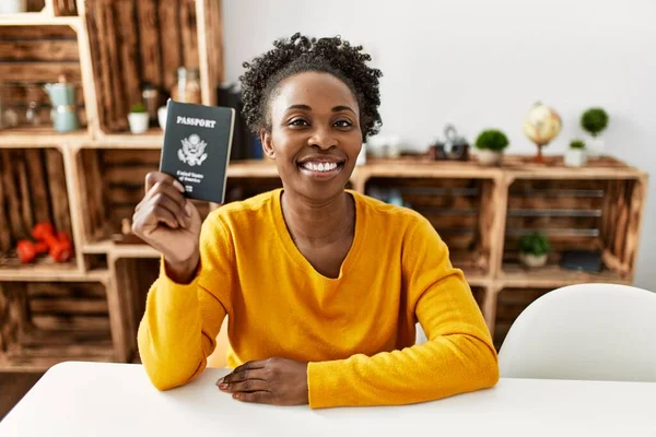 African american woman holding united states passport sitting on table at home