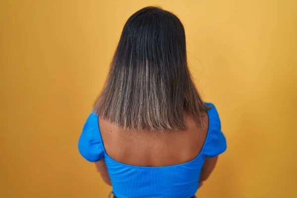 Junge Hispanische Frau Steht Auf Gelbem Hintergrund Und Blickt Rückwärts — Stockfoto