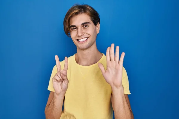 Young Man Standing Blue Background Showing Pointing Fingers Number Seven — Foto Stock