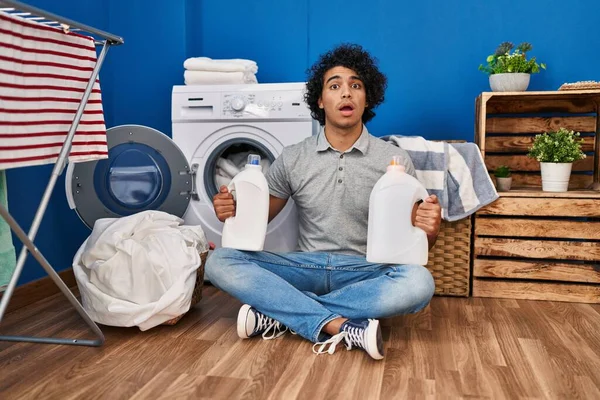Hispanic Man Curly Hair Doing Laundry Holding Detergent Bottles Afraid — Stok fotoğraf