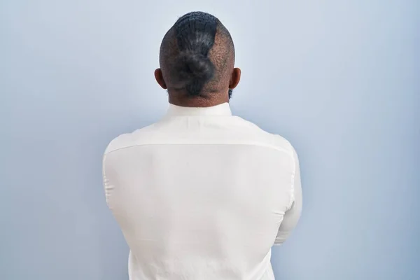 Afrykański Amerykanin Stojący Nad Niebieskim Tłem Odwracając Wzrok Skrzyżowanymi Ramionami — Zdjęcie stockowe