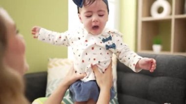 Woman and toddler standing on sofa playing at home