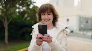 Middle age woman smiling confident using smartphone at park