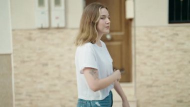 Young caucasian woman smiling confident holding key of new home at street