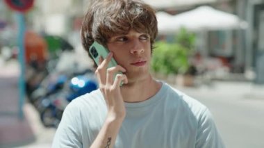 Genç sarışın adam gülümsüyor. Kendine güveniyor. Akıllı telefondan konuşuyor.