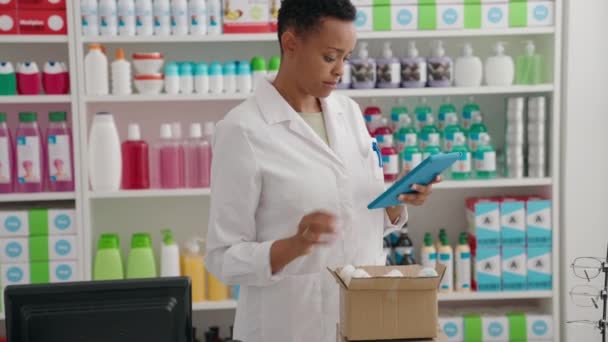 アフリカ系アメリカ人女性薬剤師が薬局でタッチパッド保持パッケージを使用 — ストック動画