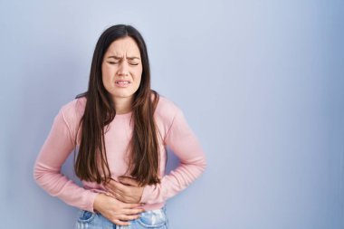 Mide bulantısı, acı verici bir hastalık yüzünden mavi arka planda duran genç esmer kadın. Ağrı kavramı. 