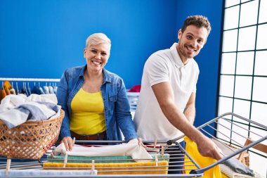 Mother and son smiling confident hanging clothes on clothesline at laundry room
