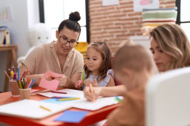 Teachers with boy and girl smiling confident having handcrafts class at kindergarten