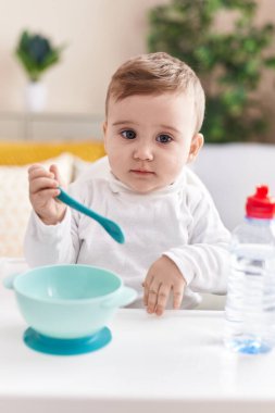 Sevimli beyaz bebek sandalyeye oturmuş, evde yemek yiyor.