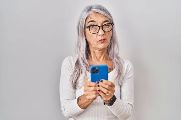 スマートフォンの入力メッセージを懐疑的かつ神経を使用して白髪の中年の女性 問題のために動揺を眉をひそめて 否定的な人 — ストック写真