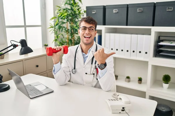 Young Hispanic Doctor Man Holding Dumbbells Pointing Thumb Side Smiling — Fotografia de Stock